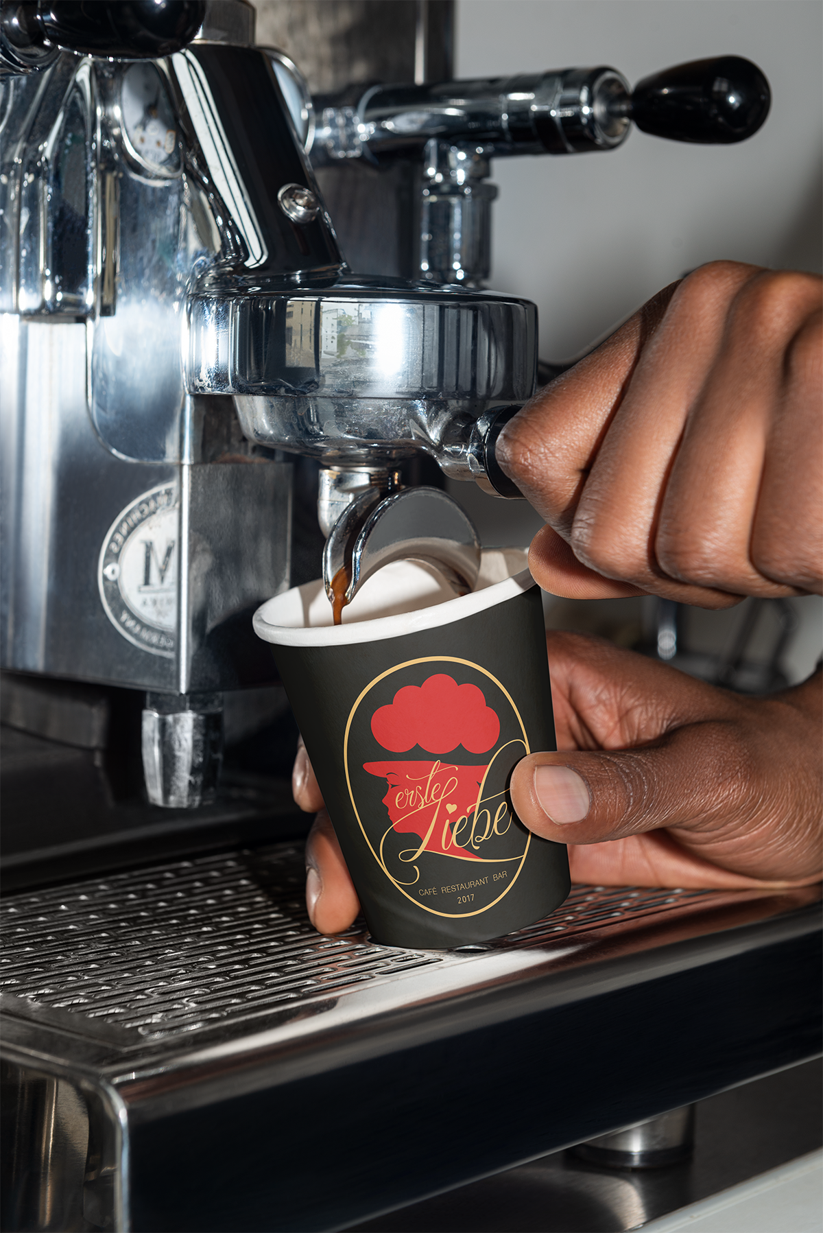 Schwarzer Espressobecher mit weißem Schriftzug unter der Siebträgermaschine